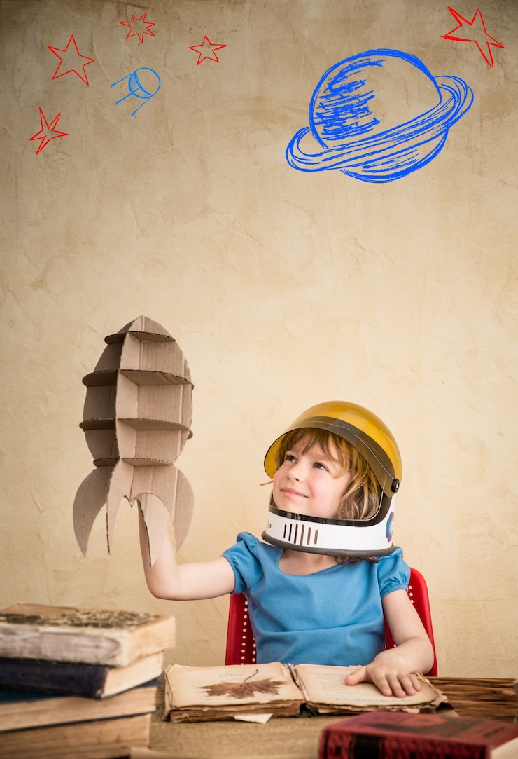Photo enfant astronaute avec une fusée jouet en carton enfant jouant à la maison concept du jour de la terre