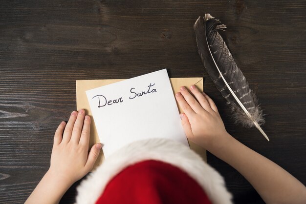 Enfant au bonnet de Noel écrit une lettre au père Noël.