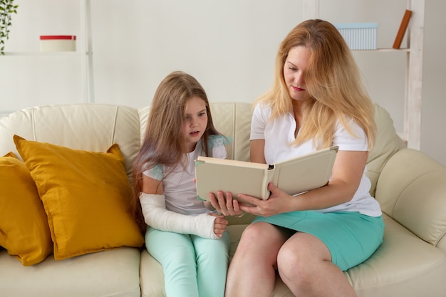 L'enfant au bras cassé et au gypse passe du temps à la maison avec sa mère. Maladies infantiles, perspectives positives et rétablissement.