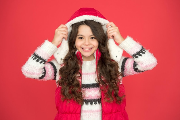 Un enfant au visage heureux ressent du bonheur et est prêt pour la célébration des vêtements chauds de vacances de noël et du nouvel an