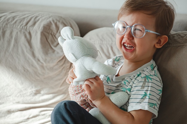 Un enfant autiste serre un jouet dans ses bras, pleure et se met en colère