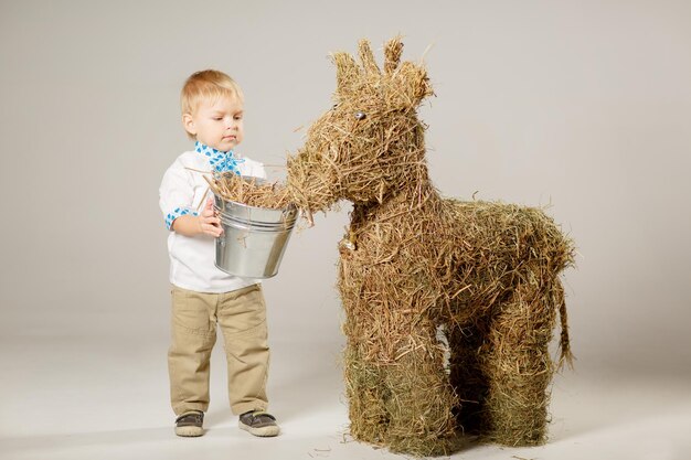 un enfant aux cheveux blonds nourrit un veau de paille concept de veau de paille pour une ferme agricole