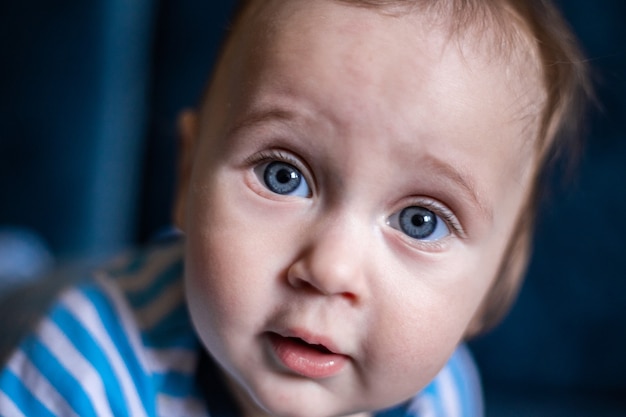 Un enfant aux grands yeux bleus regarde la caméra avec surprise un gros plan de son visage photo de haute qualité