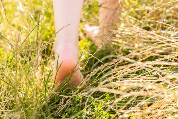 L'enfant aux pieds nus marche sur l'herbe.