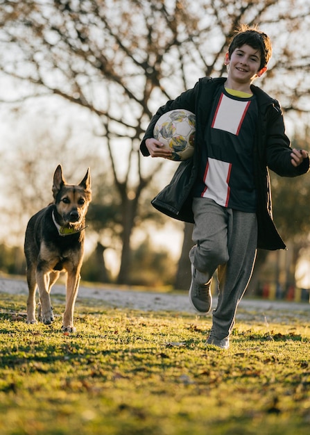 Enfant avec ballon courant à partir d'un chien jouant à un jeu de rattrapage