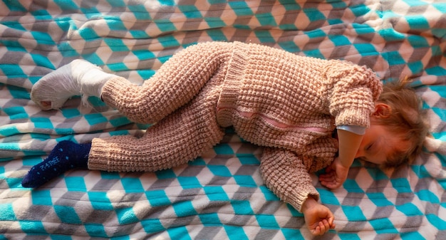 Enfant avec un bandage sur une fracture du talon de la jambe Attelle du pied droit cassée d'un tout-petit Petit garçon dormant sur une couverture bleue