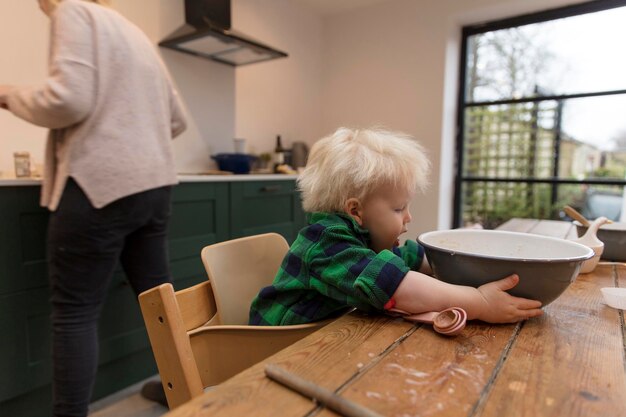 Un enfant en bas âge aidant à la cuisson dans la cuisine il tenant un bol à mélanger