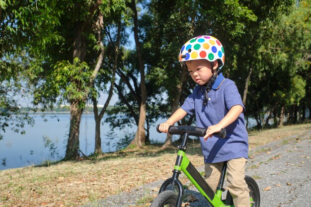 Enfant en bas âge asiatique garçon enfant portant un casque de sécurité apprendre à monter le premier vélo d'équilibre