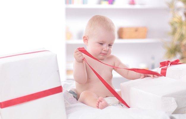 Enfant en bas âge bébé enfant assis dans présente un cadeau pour la célébration. Notion de nouvel an de Noël.