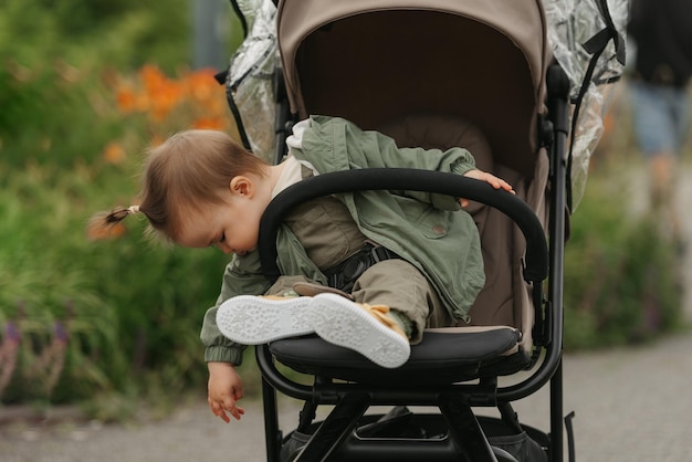 Un enfant en bas âge féminin s'assied dans la poussette un jour nuageux