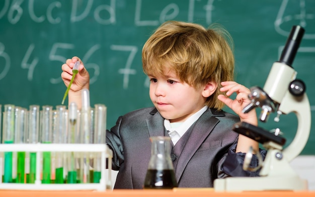 Enfant en bas âge génie bébé Concept scientifique Enfant doué et enfant prodige Kid étudier la leçon d'école de chimie Éducation scolaire Garçon utiliser un microscope et des tubes à essai dans la salle de classe Analyse chimique