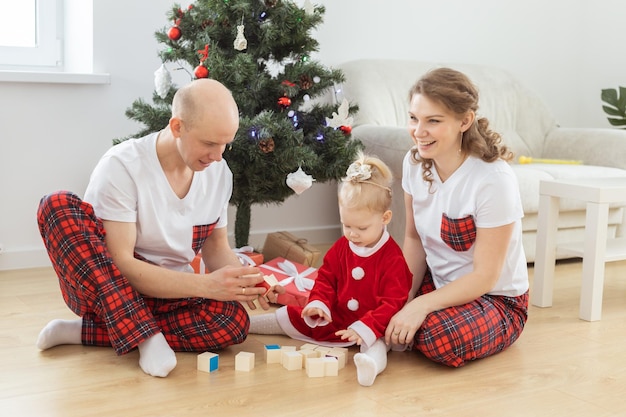 Un enfant en bas âge avec implant cochléaire joue avec ses parents sous l'arbre de noël surdité et technologies médicales innovantes pour l'aide auditive et la diversité