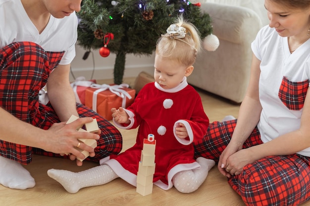 Un enfant en bas âge avec implant cochléaire joue avec ses parents sous l'arbre de noël surdité et technologies médicales innovantes pour l'aide auditive et la diversité