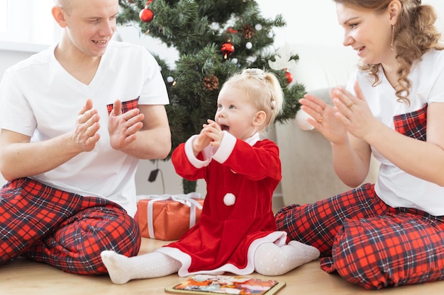 Un enfant en bas âge avec un implant cochléaire joue avec ses parents sous l'arbre de Noël surdité et des technologies médicales innovantes pour les aides auditives