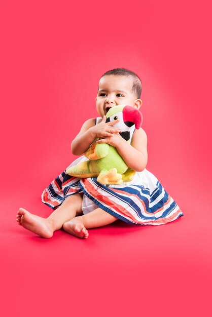 Enfant en bas âge indien ou asiatique ou nourrisson ou bébé jouant avec des jouets ou des blocs en position couchée ou assise isolé sur fond clair ou coloré