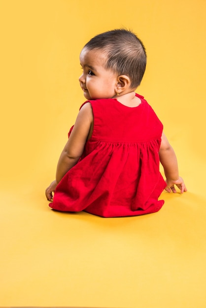 Enfant en bas âge indien ou asiatique ou nourrisson ou bébé jouant avec des jouets ou des blocs en position couchée ou assise isolé sur fond clair ou coloré