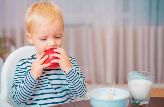 Enfant en bas âge mangeant une collation à la maison Enfant mangeant du porridge Enfant mignon garçon aux yeux bleus s'assoit à table avec une assiette et de la nourriture Nutrition saine Alimentation saine Enfant mignon bébé mangeant le petit déjeuner Nutrition bébé Mange en bonne santé