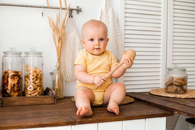 Enfant en bas âge mignon dans la cuisine en bois de la maison