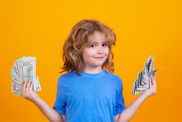 Enfant avec beaucoup d'argent billets en dollars isolés sur fond de studio jaune