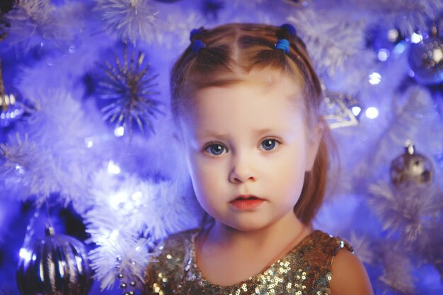 Enfant blond avec un arbre de Noël. Décoration de Noël luxueuse.