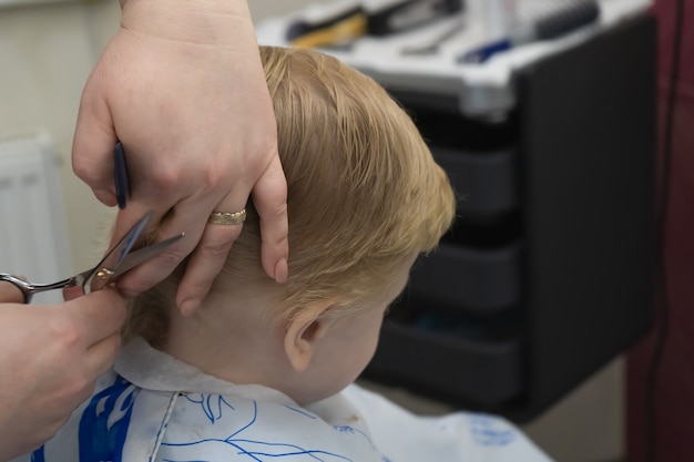 enfant blond se faisant couper les cheveux chez le coiffeur