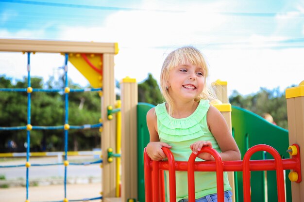 Enfant blond sourit sur l'aire de jeux