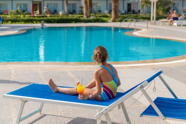 L'enfant boit un cocktail au bord de la piscine