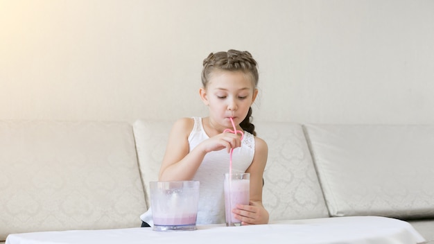 L'enfant boit un cocktail avec une paille.