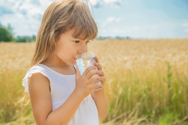 Un enfant boit de l'eau sur le fond du champ