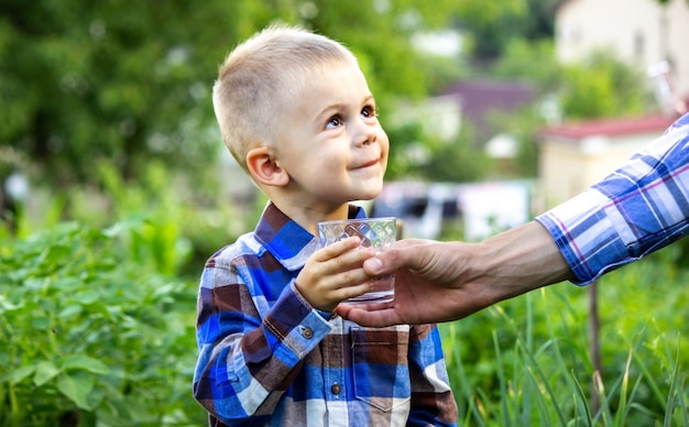 L'enfant boit de l'eau propre dans la nature.