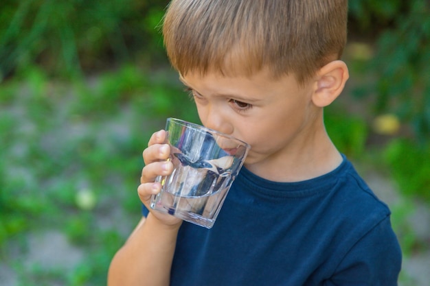 L'enfant boit de l'eau d'un verre Mise au point sélective