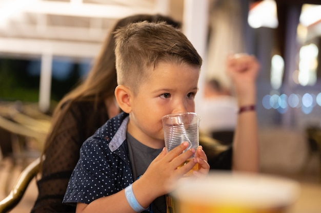 L'enfant boit un verre d'eau dans une cabane de montagne. photo de haute qualité