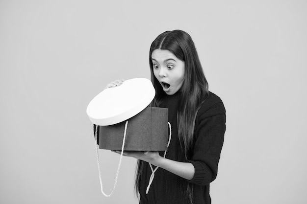 Enfant avec boîte-cadeau sur fond de studio isolé Dons pour anniversaire d'enfants Émotions surprises d'une jeune adolescente