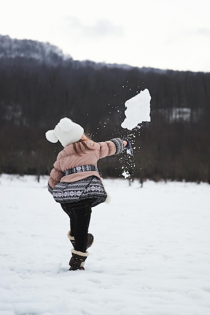 Enfant en bonnet tricoté et veste chaude s'amuse et passe activement des vacances d'hiver dans la nature