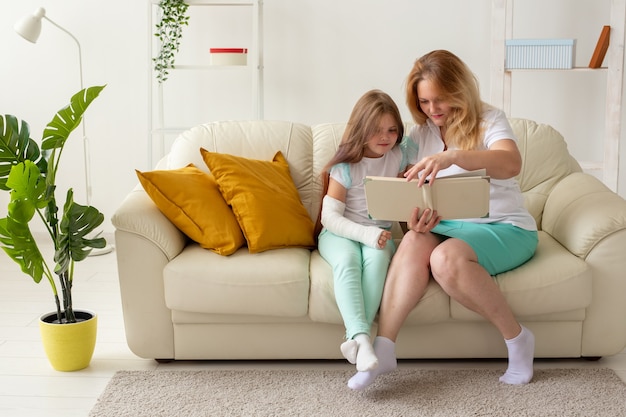 L'enfant avec un bras cassé et du gypse passe du temps à la maison avec sa mère. Maladies infantiles, un point positif