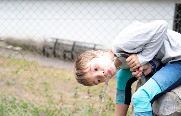 Enfant buvant de l'eau à la fontaine