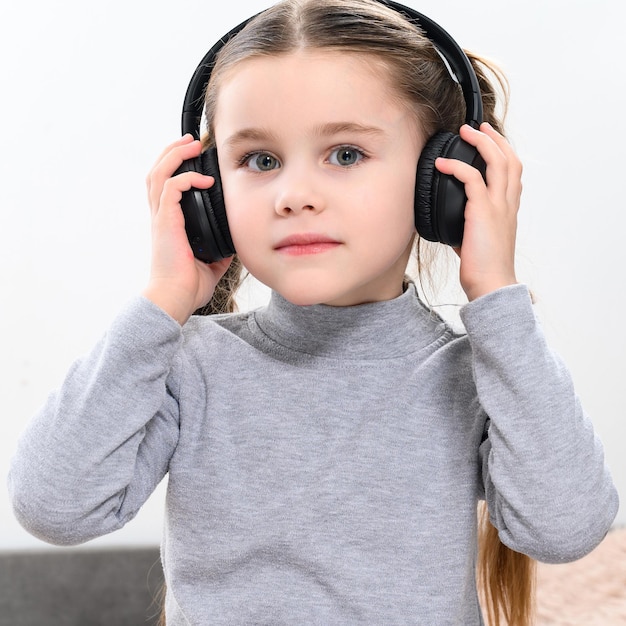 Un enfant avec un casque sur fond blanc une fille joyeuse et belle avec un casque