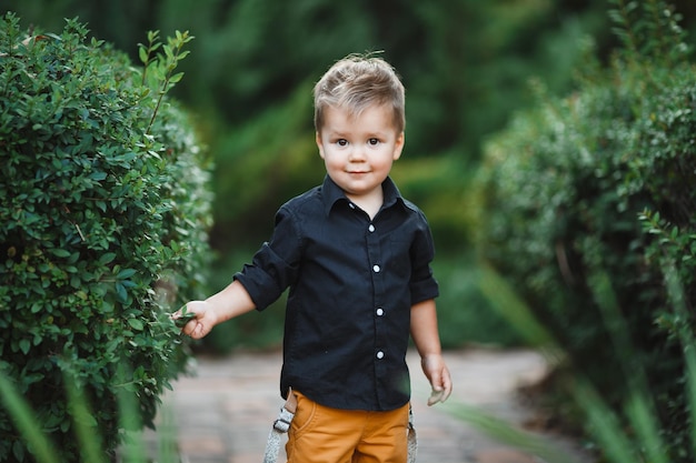 Enfant caucasien blanc avec un sourire marchant dans le parc sur un fond d'arbres verts