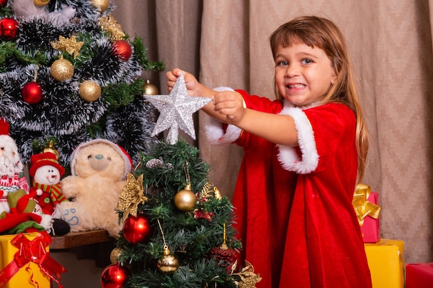 Un enfant caucasien organise la décoration de l'arbre de noël avec un concept d'idées festives de noël amusant et joyeux