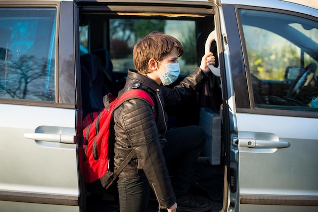 Enfant caucasien portant un masque facial debout près de la porte d'une camionnette