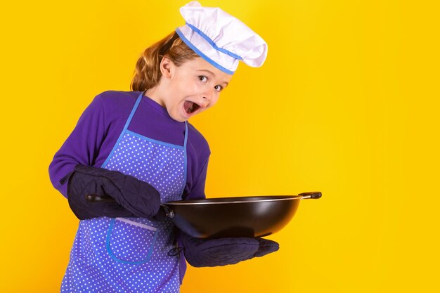 Enfant chef cuisinier avec casserole Enfant en uniforme de cuisinier Enfant de chef isolé sur fond jaune Enfant mignon pour être un chef Enfant habillé comme un chapeau de chef