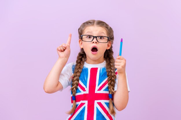 Un enfant en chemise avec un drapeau britannique a ouvert la bouche avec surprise et a pointé votre annonce.