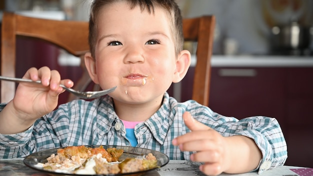 Enfant en chemise mangeant de près.