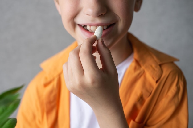 Enfant en chemise orange souriant et prévoyant de manger une grosse vitamine