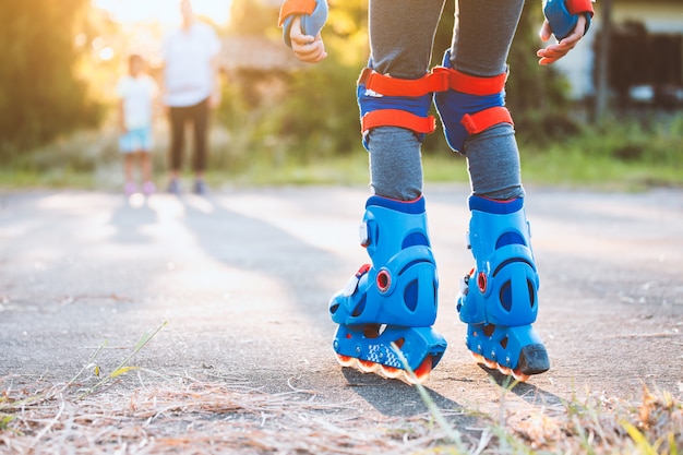 Enfant à cheval sur des patins à roulettes dans le parc