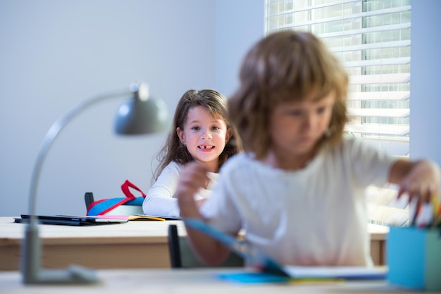 Enfant en classe à l'école garçon et fille assis au bureau et écrivant un texte