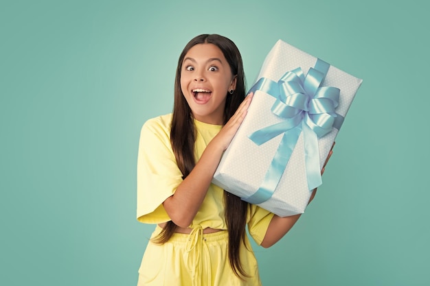 Enfant avec coffret cadeau sur fond de studio isolé Dons pour anniversaire d'enfants visage surpris surprise émotions d'adolescente