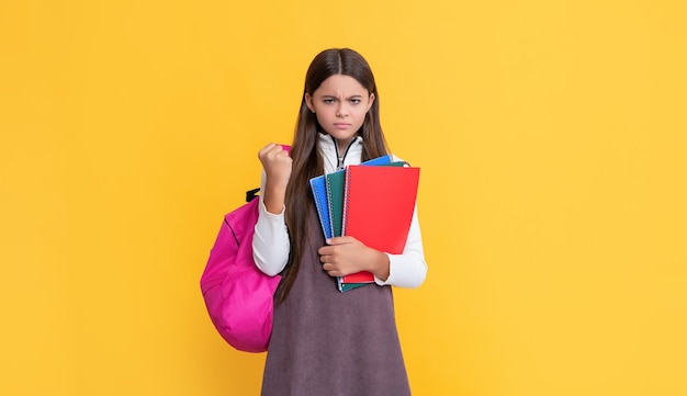 Enfant en colère avec sac à dos scolaire et cahier d'exercices sur fond jaune