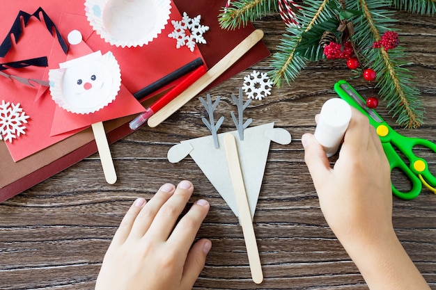 L'enfant colle les pièces Noël Renne stics marionnettes Artisanat fait main pour les enfants