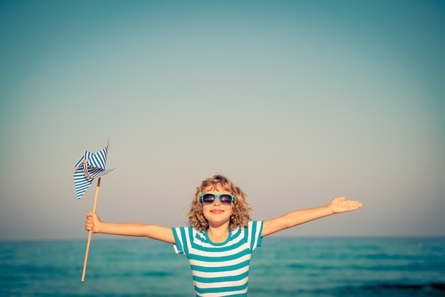 enfant contre la mer bleue et le ciel tenant un moulinet en vacances d'été